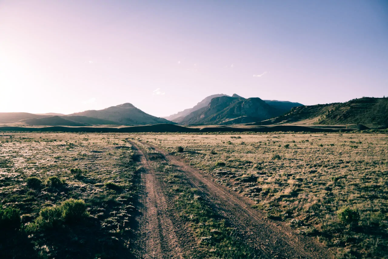 Open ranchland with rugged mountain backdrop