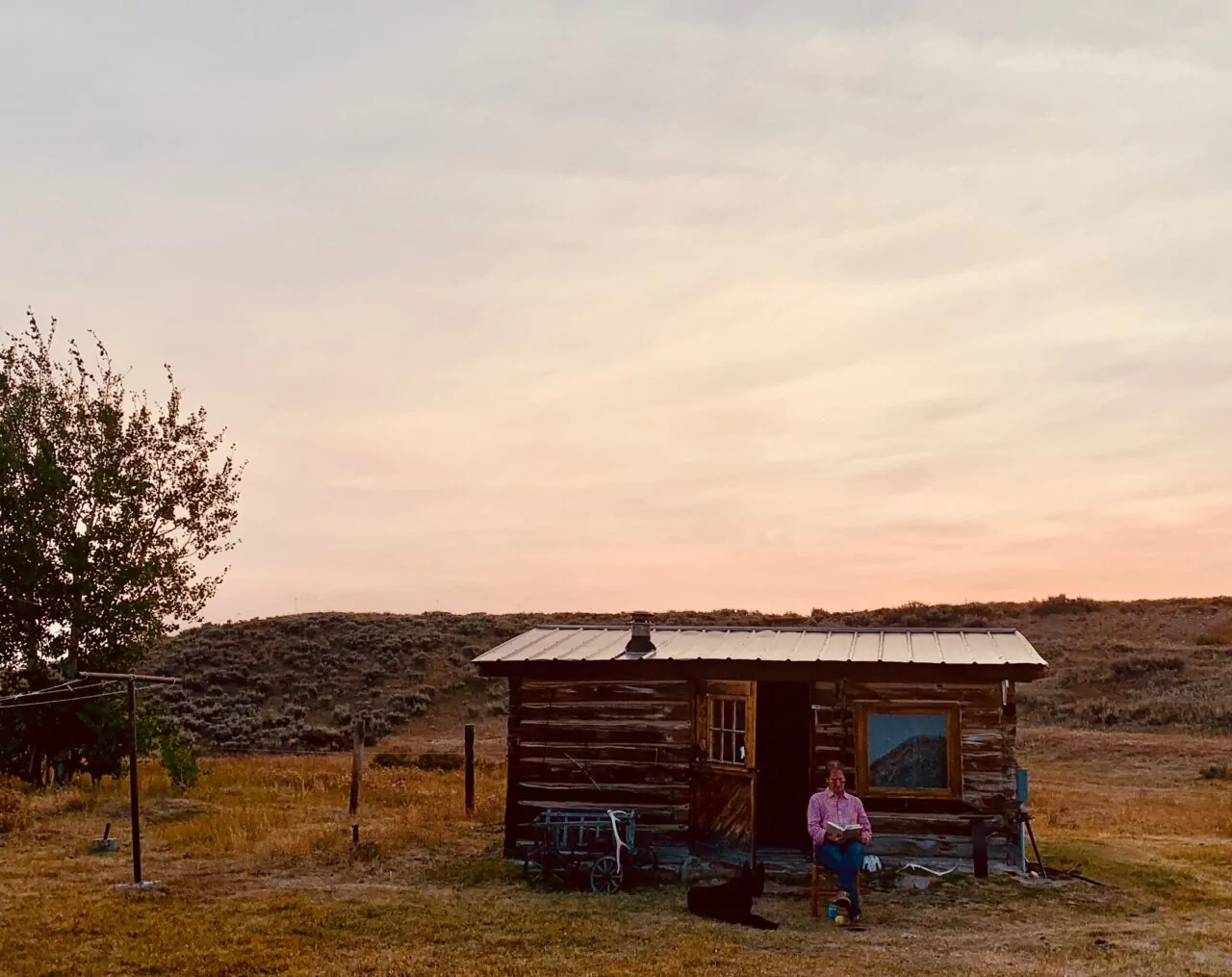 MRG cabin sunset scene with person and dog in open field.
